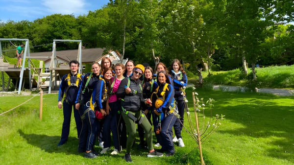Eine Gruppe von Schülerinnen und Schülern steht gemeinsam in einem grünen Außenbereich auf dem Campus des Edmund Rice College.