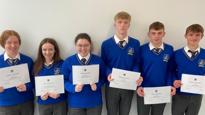 Schüler des Edmund Rice College halten stolz ihre Urkunden vor weißem Hintergrund.