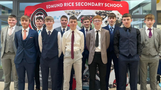 Eine Gruppe Schülerinnen und Schüler der Edmund Rice Secondary School steht vor dem Schuldach mit dem Schulnamen.