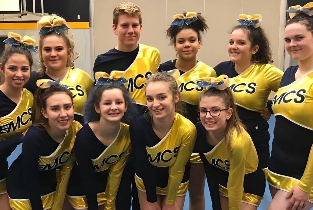 Die Cheerleading-Mannschaft der Edward Milne Community School posiert gemeinsam in der Sporthalle.