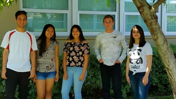 Eine Gruppe von fünf Schülerinnen und Schülern steht vor einem grünen Gebäude auf dem Campus der El Cajon Valley High School.