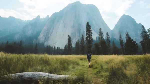 Eine Person geht auf einem grasbewachsenen Weg in einer Berglandschaft auf dem Gelände der Elgin Park Secondary School.
