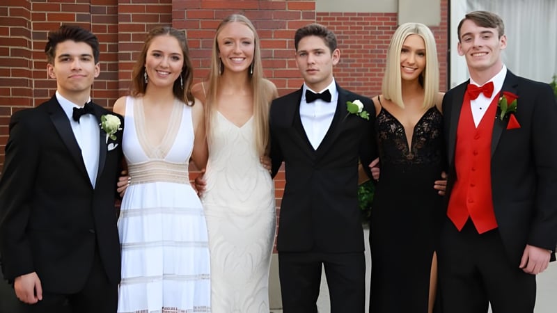 Eine Gruppe von sechs gut gekleideten Personen posiert vor dem Backsteingebäude der Elgin Park Secondary School.