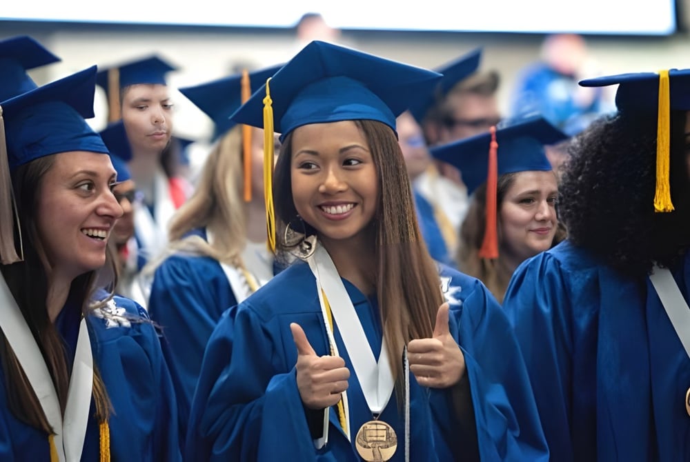 Eine Gruppe von Absolventinnen und Absolventen des Elizabeth College feiert in blauen Talaren ihren Studienabschluss.