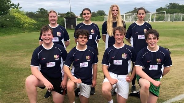 Eine Gruppe Schülerinnen und Schüler des Elizabeth College posiert gemeinsam auf einem Fußballfeld mit Tor im Hintergrund.