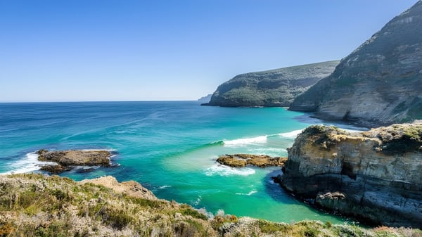 Küstenlandschaft mit felsigen Klippen und türkisblauem Wasser nahe Elizabeth College.