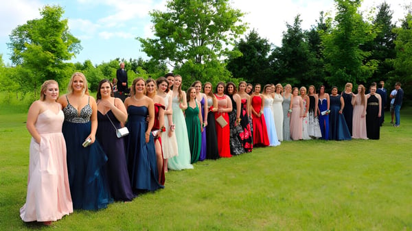 Eine Gruppe junger Frauen in formellen Kleidern steht auf einer Wiese auf dem Gelände der Elmvale District High School.