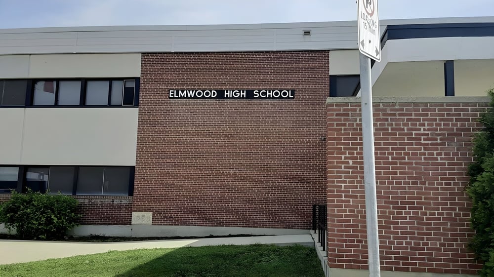 Das Backsteingebäude mit dem Schriftzug Elmwood High School ist von einer Grünfläche umgeben.
