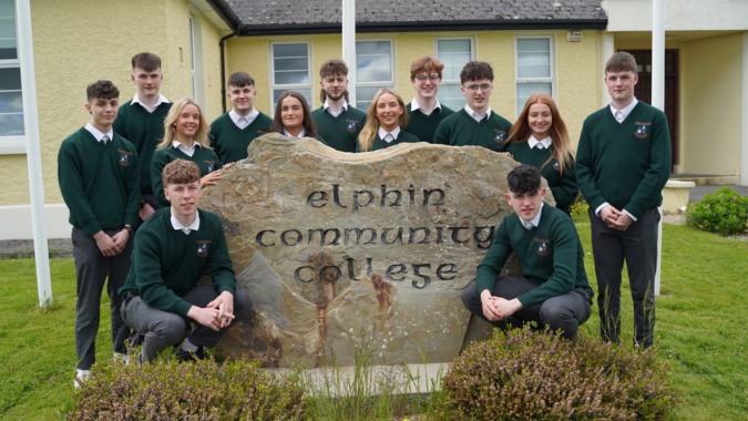 Eine Gruppe Schülerinnen und Schüler posiert vor dem großen Steinschild des Elphin Community College.