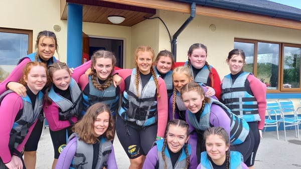 Eine Gruppe Schülerinnen des Elphin Community College steht vor einem Holzgebäude während einer Outdoor-Aktivität.