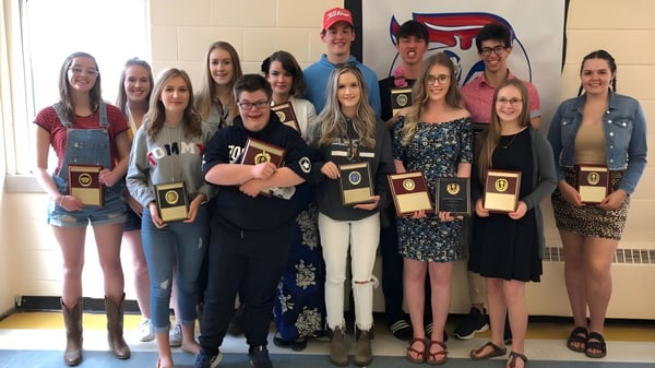 Eine Gruppe Schülerinnen und Schüler der Elwood Regional High posiert gemeinsam mit Pokalen in einer schulischen Umgebung.