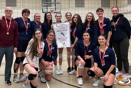 Eine Gruppe sportlich gekleideter Schülerinnen der Elwood Regional High hält gemeinsam einen Pokal in der Sporthalle.