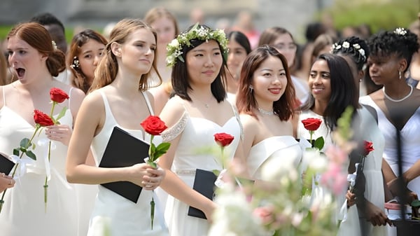 Eine Gruppe junger Schülerinnen der Emma Willard School steht mit roten Rosen im Freien vor Gebäuden und Grünflächen.