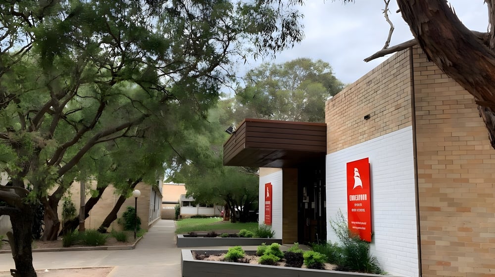 Das Backsteingebäude der Endeavour Sports High School steht von Bäumen umgeben in einer grünen Außenanlage mit gepflastertem Weg.