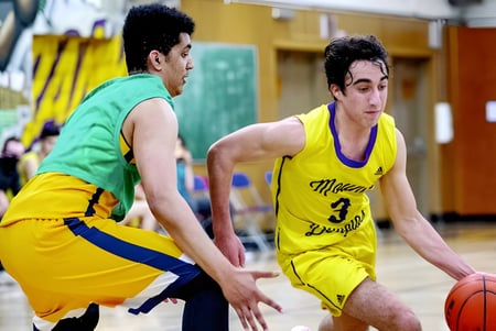 Zwei Schülerinnen und Schüler spielen Basketball auf dem Sportplatz der Enver Creek Secondary School.