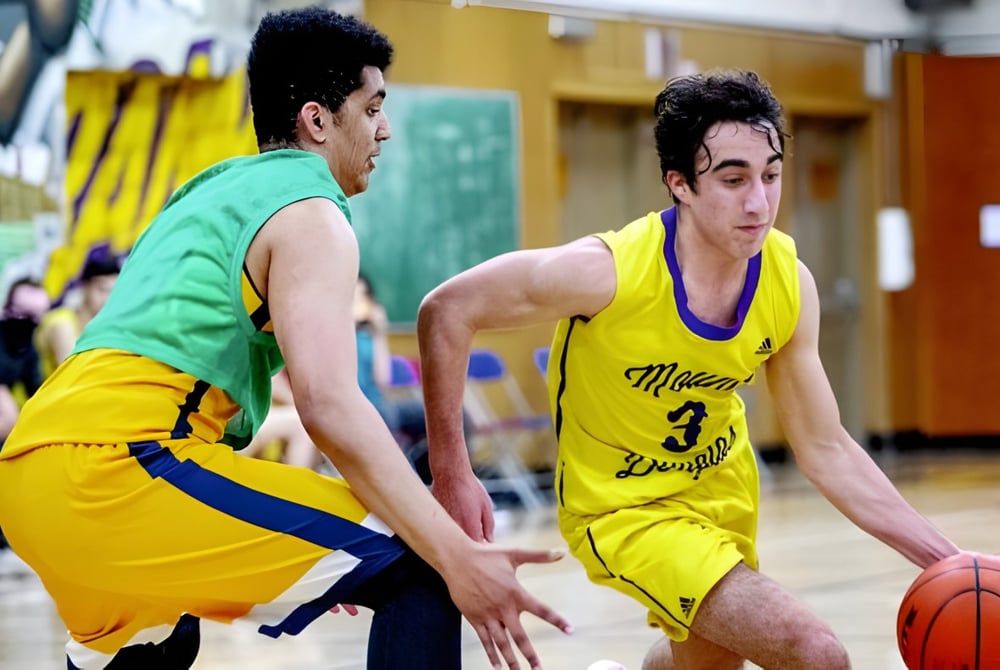 Zwei Schülerinnen und Schüler spielen Basketball auf dem Sportplatz der Enver Creek Secondary School.