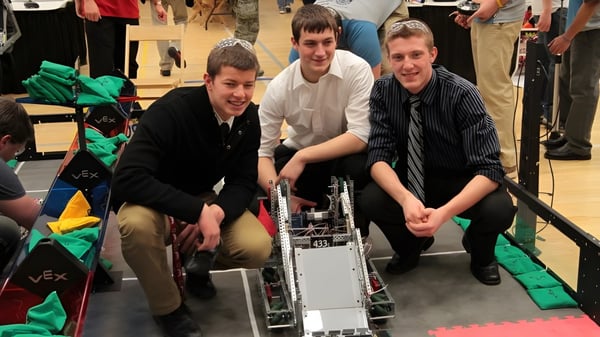 Schüler der Enver Creek Secondary School arbeiten gemeinsam an einem Roboter in der Werkstatt.