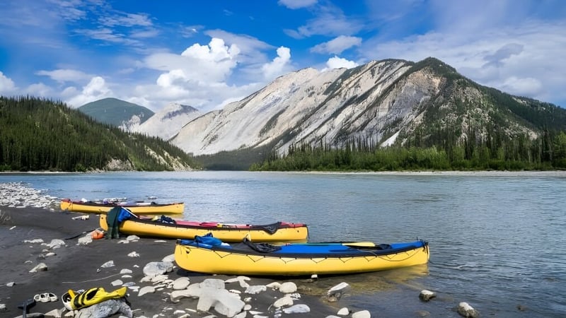 Der ruhige Bergsee mit gelben Booten vor den Bergen auf dem Gelände der Enver Creek Secondary School.