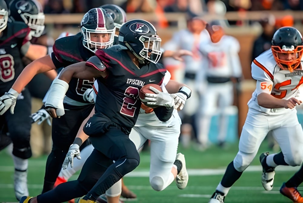 Schüler der Episcopal High School spielen ein Fußballspiel auf dem Sportplatz mit Zuschauern im Hintergrund.
