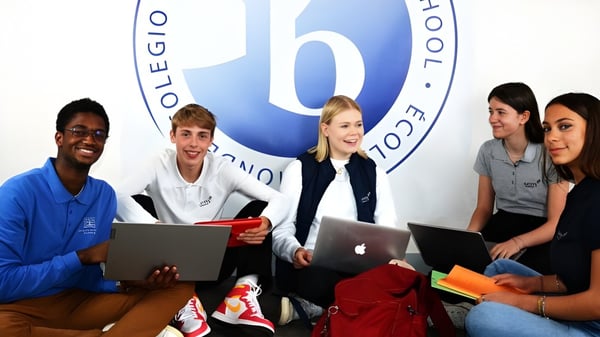 Eine Gruppe von Schülern mit Laptops sitzt zusammen auf dem Campus der Episcopal Sem' De Walbourg.