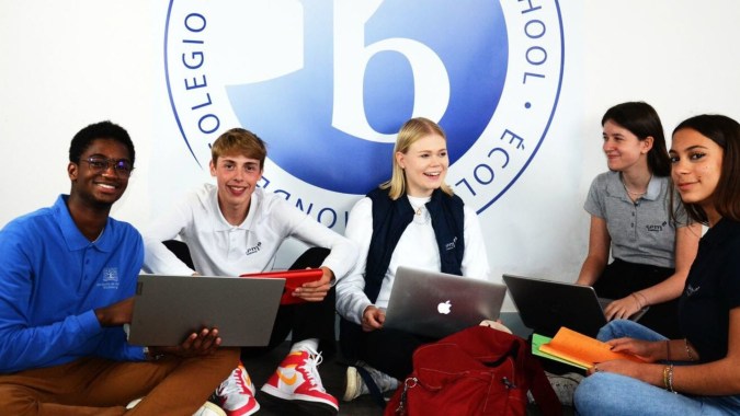Eine Gruppe von Schülern sitzt mit Laptops und Tablets zusammen auf dem Campus der Episcopal Sem' De Walbourg.