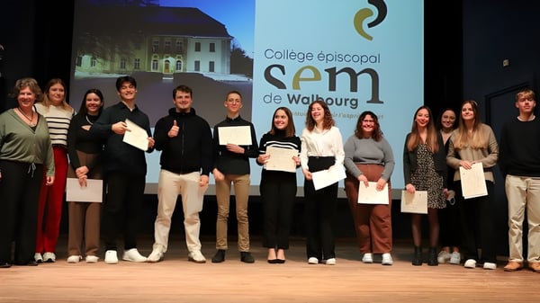Eine Gruppe von Schülerinnen und Schülern der Episcopal Sem' De Walbourg steht auf der Bühne und hält Zertifikate in den Händen.