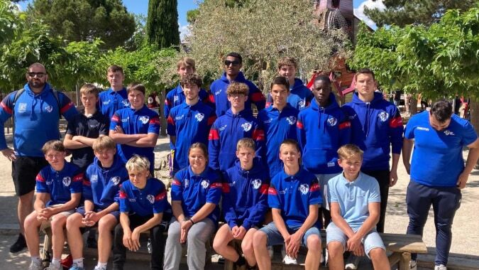 Eine Gruppe junger Fußballspielerinnen und Fußballspieler steht gemeinsam vor einer grünen Außenanlage auf dem Campus der Episcopal Sem' De Walbourg.