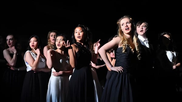 Eine Gruppe Schülerinnen des Epsom College führt auf einer abgedunkelten Bühne ein Theaterstück auf.