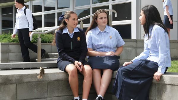 Eine Gruppe Schülerinnen der Epsom Girls Grammar School sitzt auf den Stufen des Schulgebäudes und unterhält sich.