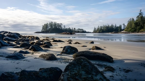Ein ruhiger Strand mit Felsen und bewaldeter Küste unter bewölktem Himmel nahe der Eric Hamber Secondary School.