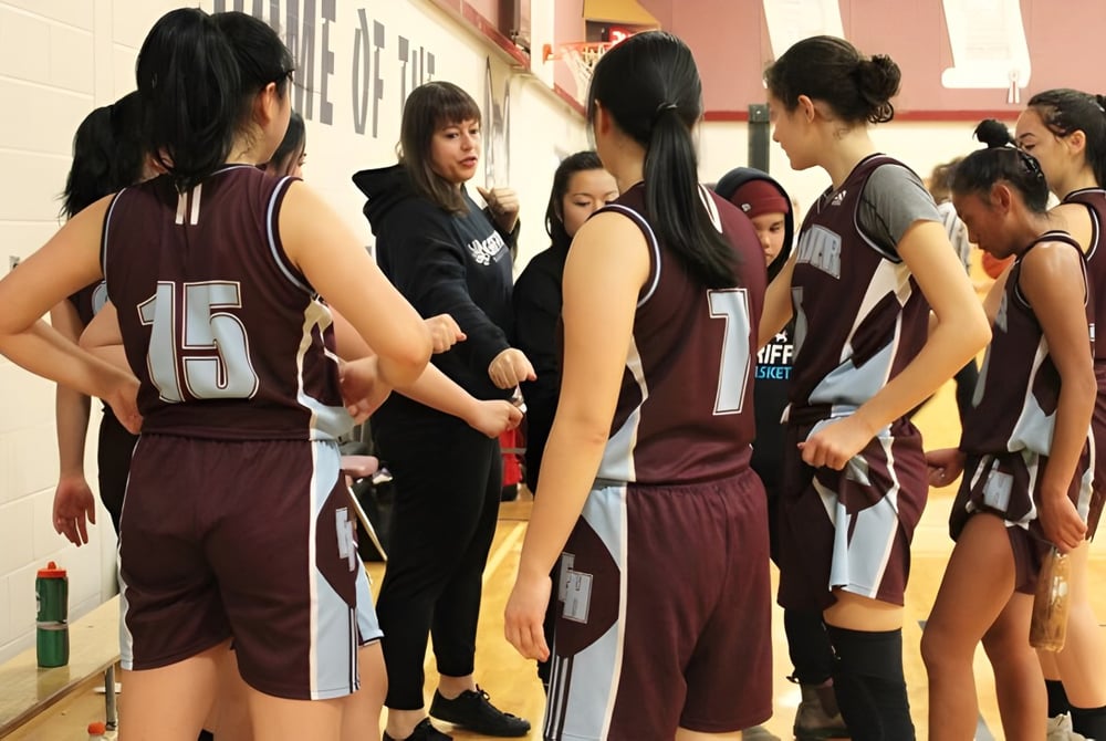 Eine Gruppe Schülerinnen der Eric Hamber Secondary School steht in Sportkleidung gemeinsam in einem Flur des Schulgebäudes.