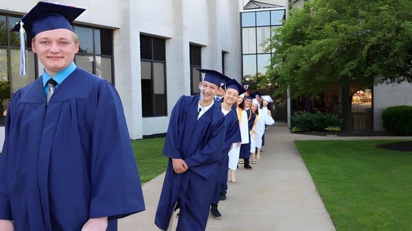 Eine Gruppe von Absolventen steht in blauen Talaren und Hüten auf dem Campus der Erie First Christian Academy.
