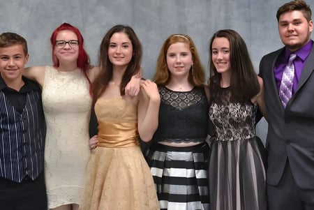 Sechs Personen in formeller Kleidung posieren gemeinsam vor grauem Hintergrund auf einem Foto der Erie First Christian Academy.