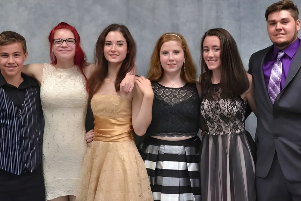 Sechs Personen in formeller Kleidung posieren gemeinsam vor grauem Hintergrund auf einem Foto der Erie First Christian Academy.