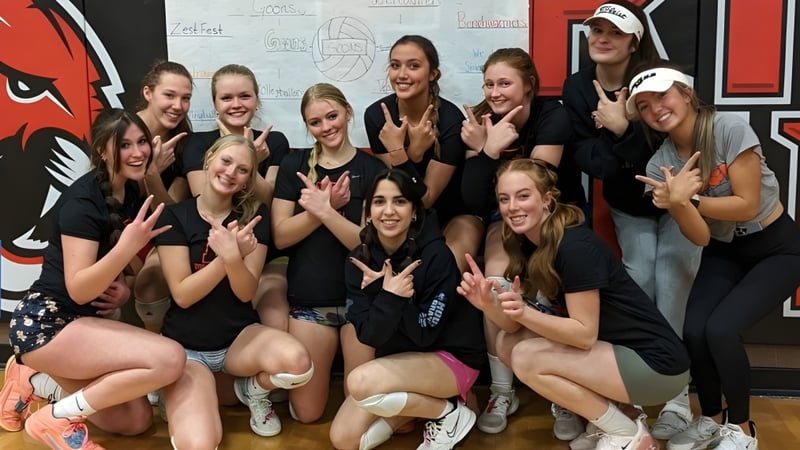 Eine Gruppe junger Frauen in schwarzen Shirts posiert gemeinsam vor einer Wand mit Grafiken auf dem Campus der Erie High School.