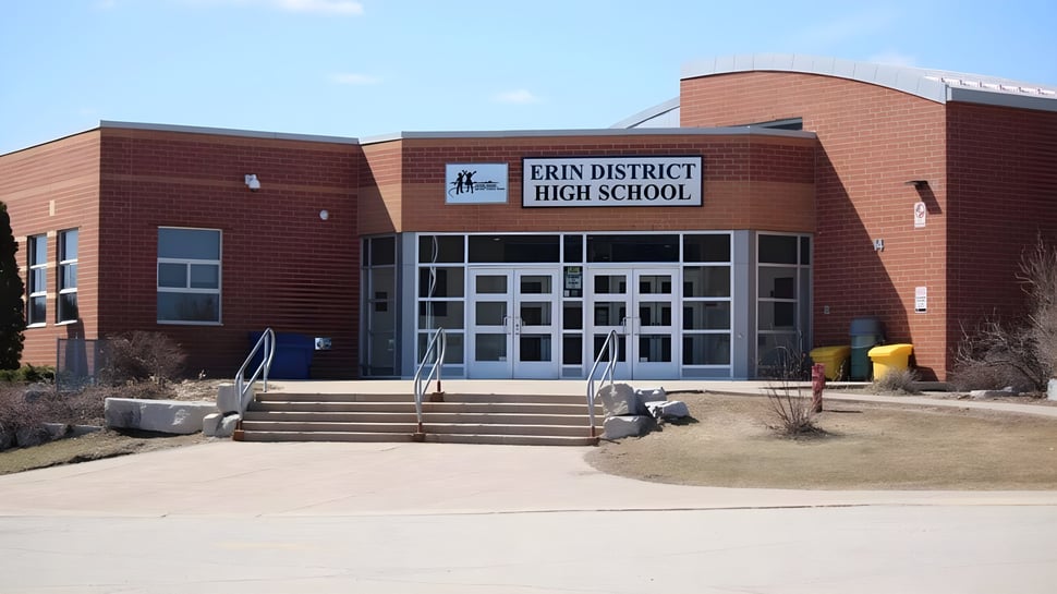 Das Backsteingebäude der Erin District High School mit einem umliegenden Grünbereich und Landschaftselementen.
