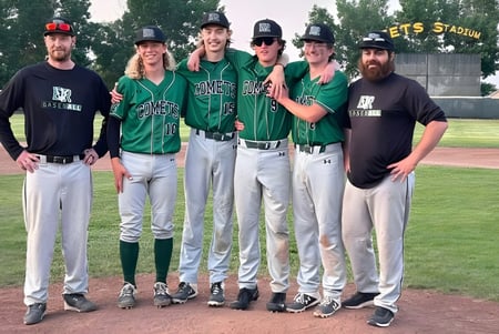 Eine Gruppe von fünf Baseballspielerinnen und -spielern der Erle Rivers High School steht gemeinsam auf dem Baseballfeld vor einem Stadion.