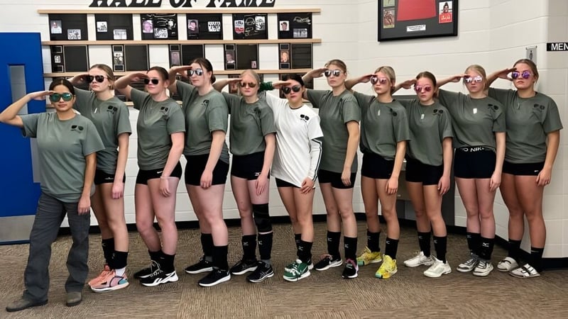 Eine Gruppe Schülerinnen der Erle Rivers High School steht vor einer Hall of Fame Wand auf dem Schulgelände.