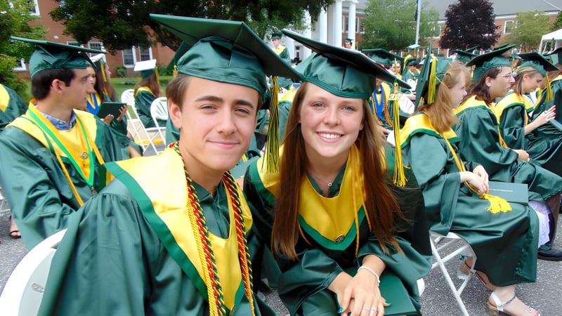 Zwei Absolventen der Ernestown Secondary School in grünen Talaren stehen zusammen und lächeln während der Abschlussfeier.