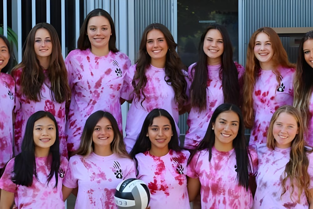 Eine Gruppe Schülerinnen der Escondido Charter High School steht vor einem grauen Metallgebäude und trägt pinke Batikshirts.