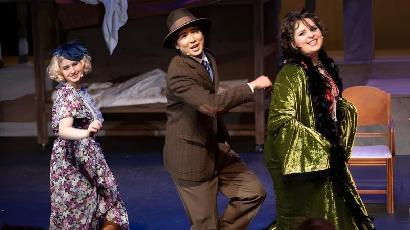 Drei Schülerinnen und Schüler der Escondido Charter High School stehen in historischen Kostümen auf der Theaterbühne.