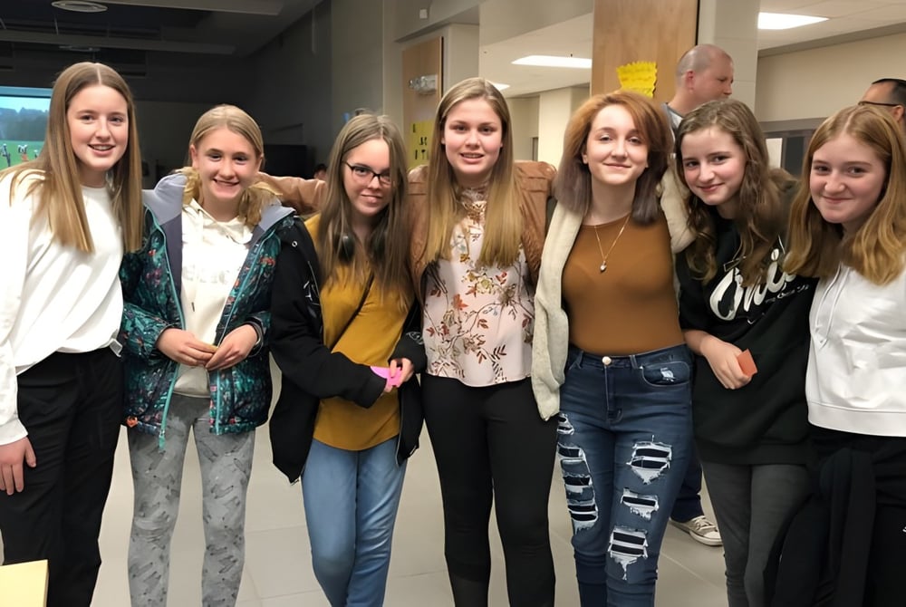 Eine Gruppe lächelnder Schülerinnen steht gemeinsam im Flur der Essex District High School.