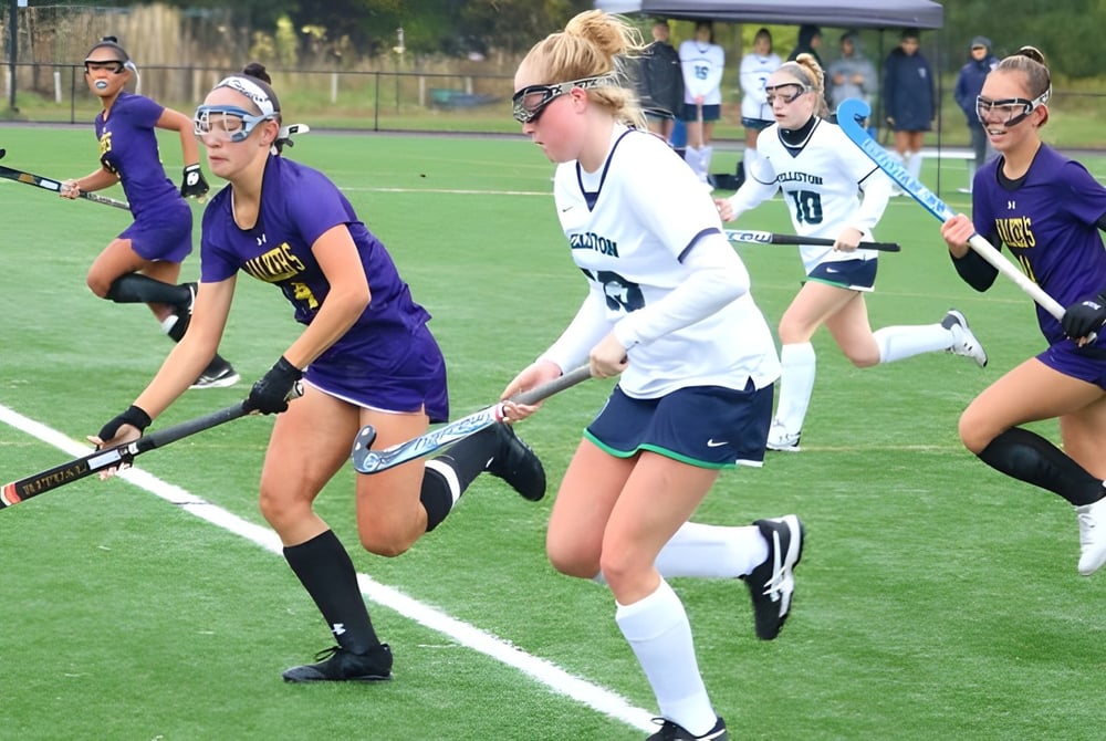Schülerinnen der The Ethel Walker School spielen ein Feldhockeyspiel auf einem Rasenplatz.
