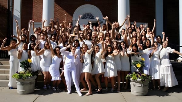 Schülerinnen der The Ethel Walker School versammeln sich auf den Stufen eines Backsteingebäudes und heben die Arme in Feierpose.