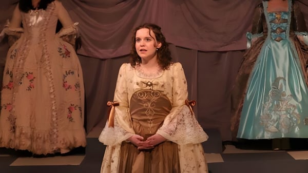 Eine Frau in einem kunstvoll verzierten Kleid steht vor einem Vorhang auf einer Bühne im Eugene School District.