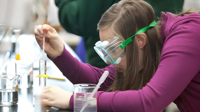 Eine Schülerin des Eugene School District führt im Labor ein wissenschaftliches Experiment mit verschiedenen Glasgeräten durch.