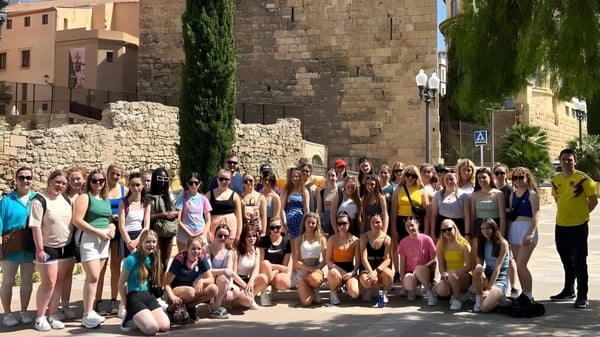 Eine große Gruppe Schüler auf dem Außenbereich der Eureka Secondary School vor historischen Steingebäuden und Grünflächen.