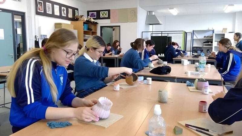 Schüler der Eureka Secondary School tragen blaue Uniformen und organisieren Materialien in einem Klassenzimmer.