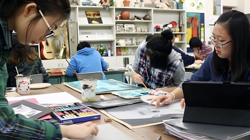 Schüler der Evan Hardy Collegiate arbeiten gemeinsam im Kunststudio mit verschiedenen Malutensilien im Hintergrund.