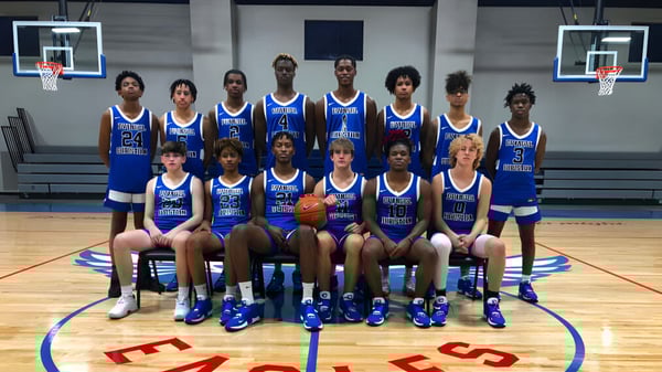 Eine Gruppe von Schülerinnen und Schülern der Evangel Christian Academy posiert gemeinsam auf dem Basketballfeld mit Basketballkörben im Hintergrund.